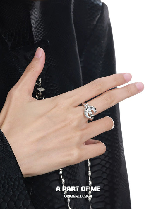 A hand wearing a bone orchid moon ring by A PART OF ME featuring a unique design and sparkling details
