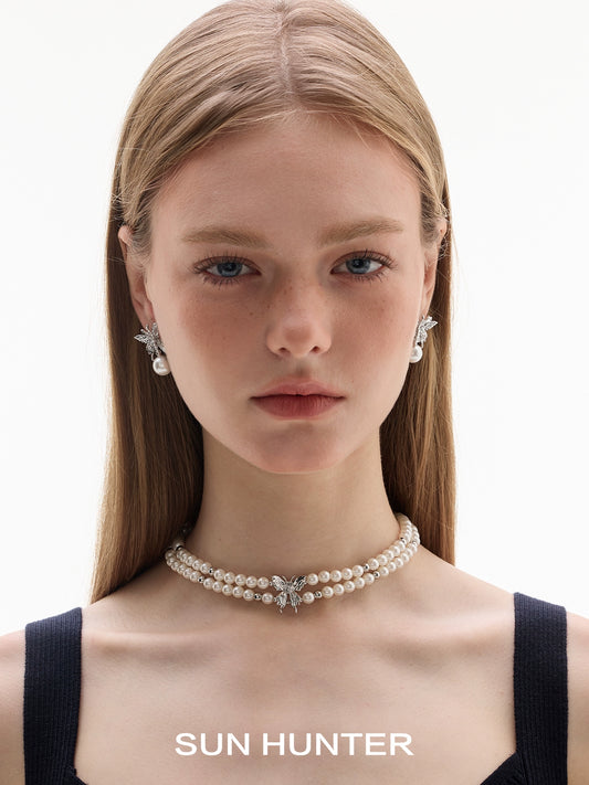 Model showcasing SUN HUNTER butterfly pearl earrings paired with a pearl choker necklace