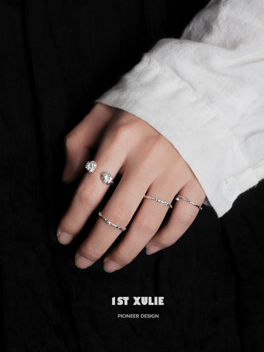 Two minimalist silver rings showcased on a hand with a white shirt, highlighting elegant simplicity