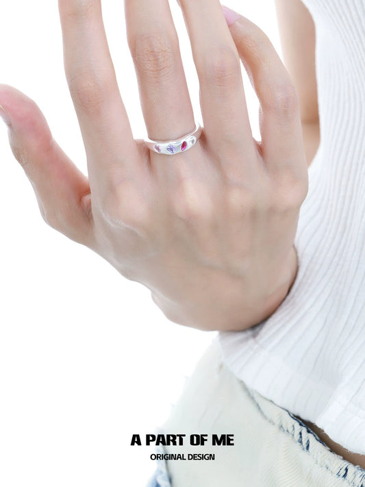 A hand wearing a rainbow zircon love ring featuring colorful stones for a unique and stylish look