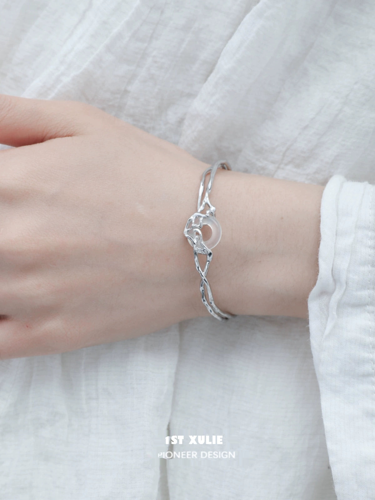 Elegant 1STXULIE Agate Silver Bracelet with a Unique Twisted Design on a Model's Wrist