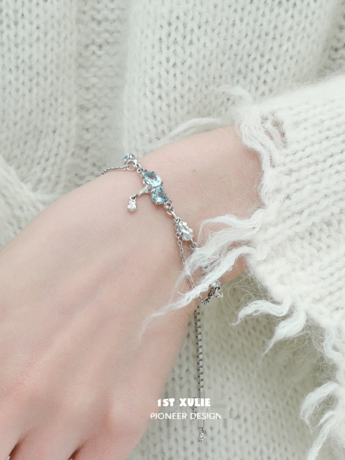 Delicate blue moonstone bracelet with silver accents, styled on a hand wearing a cozy sweater