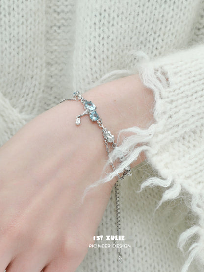Delicate blue moonstone bracelet with silver accents, styled on a hand wearing a cozy sweater