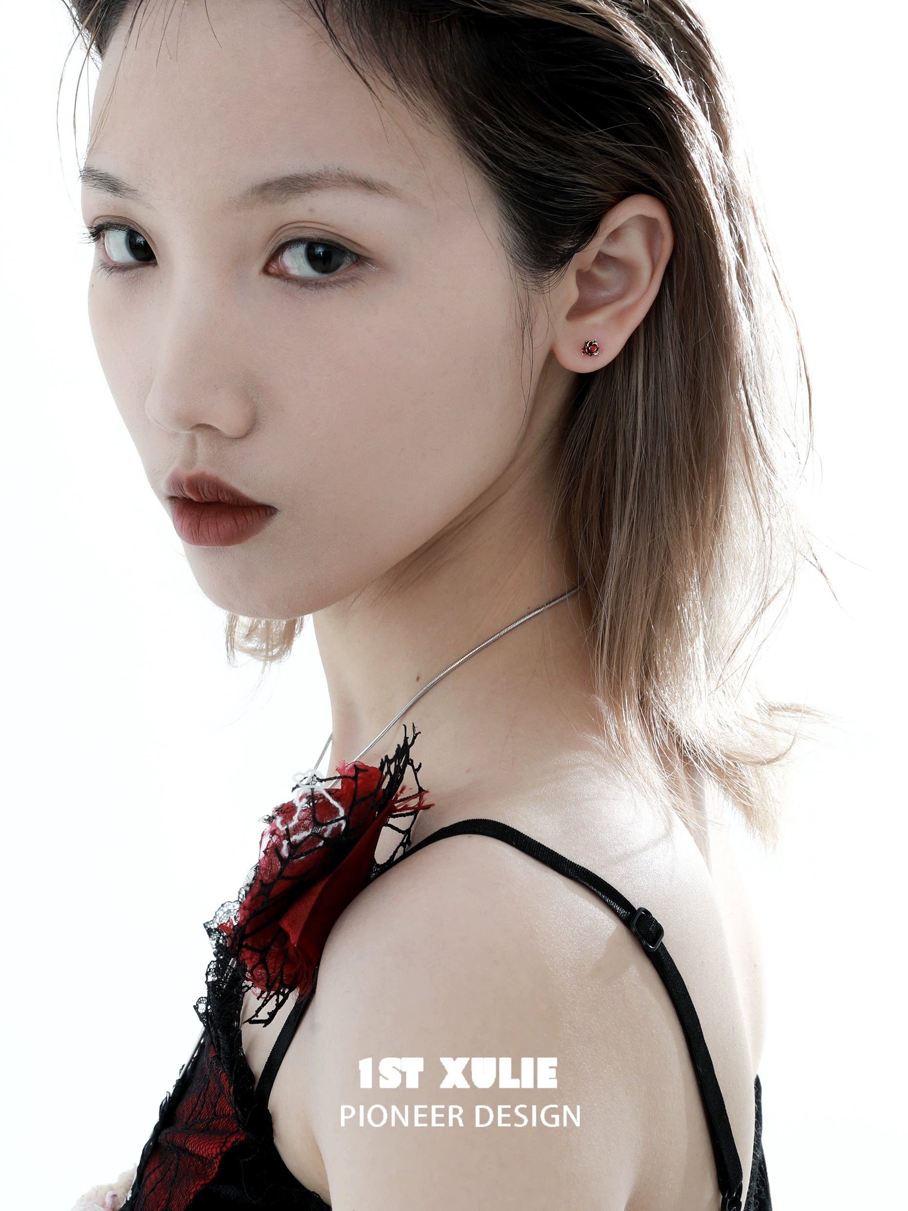 Model wearing crimson and azure rose stud earrings, showcasing elegant design and unique color combination