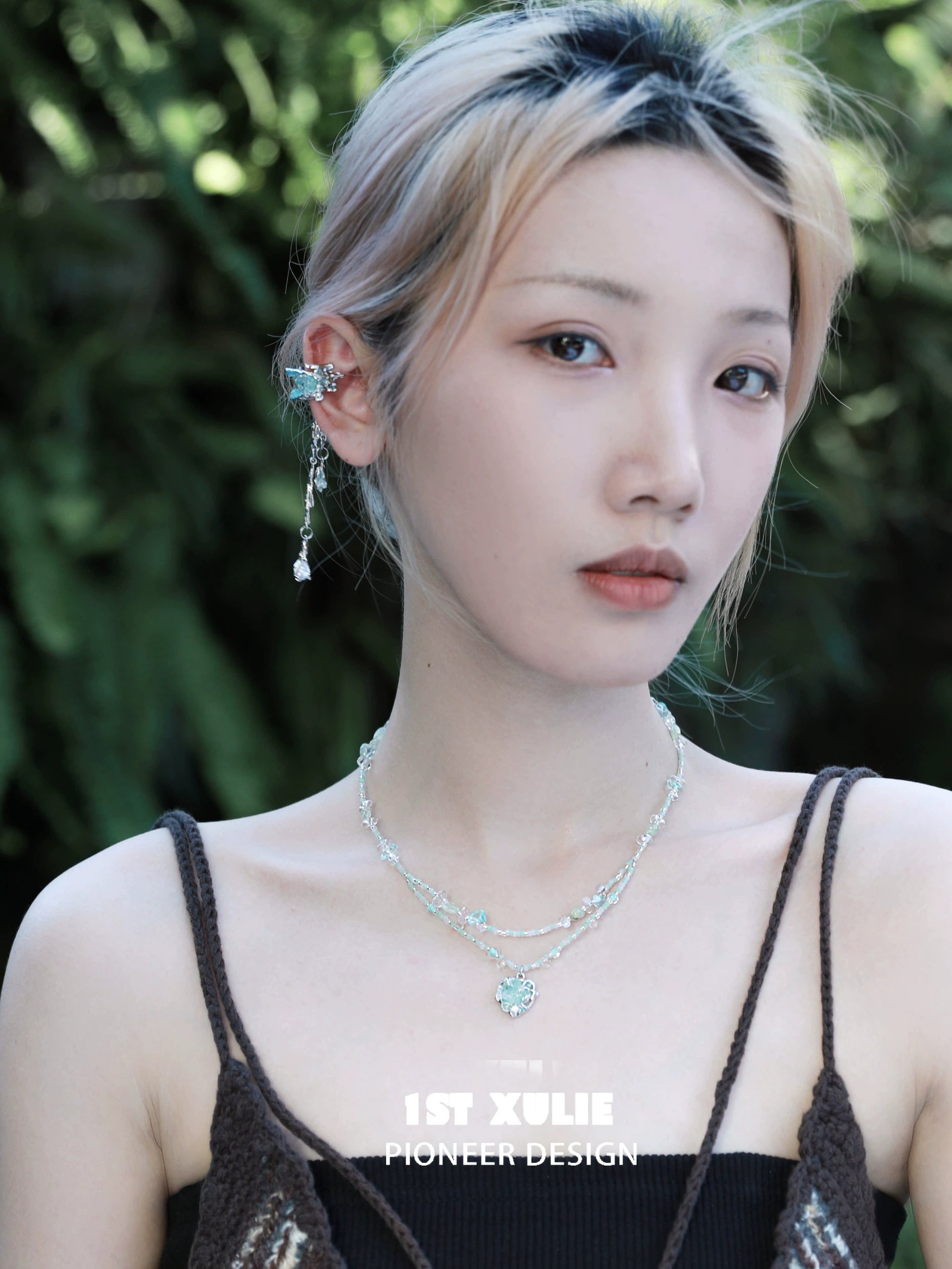 Model wearing 1STXULIE crystal tassel ear clips with stylish layered necklaces in an outdoor setting