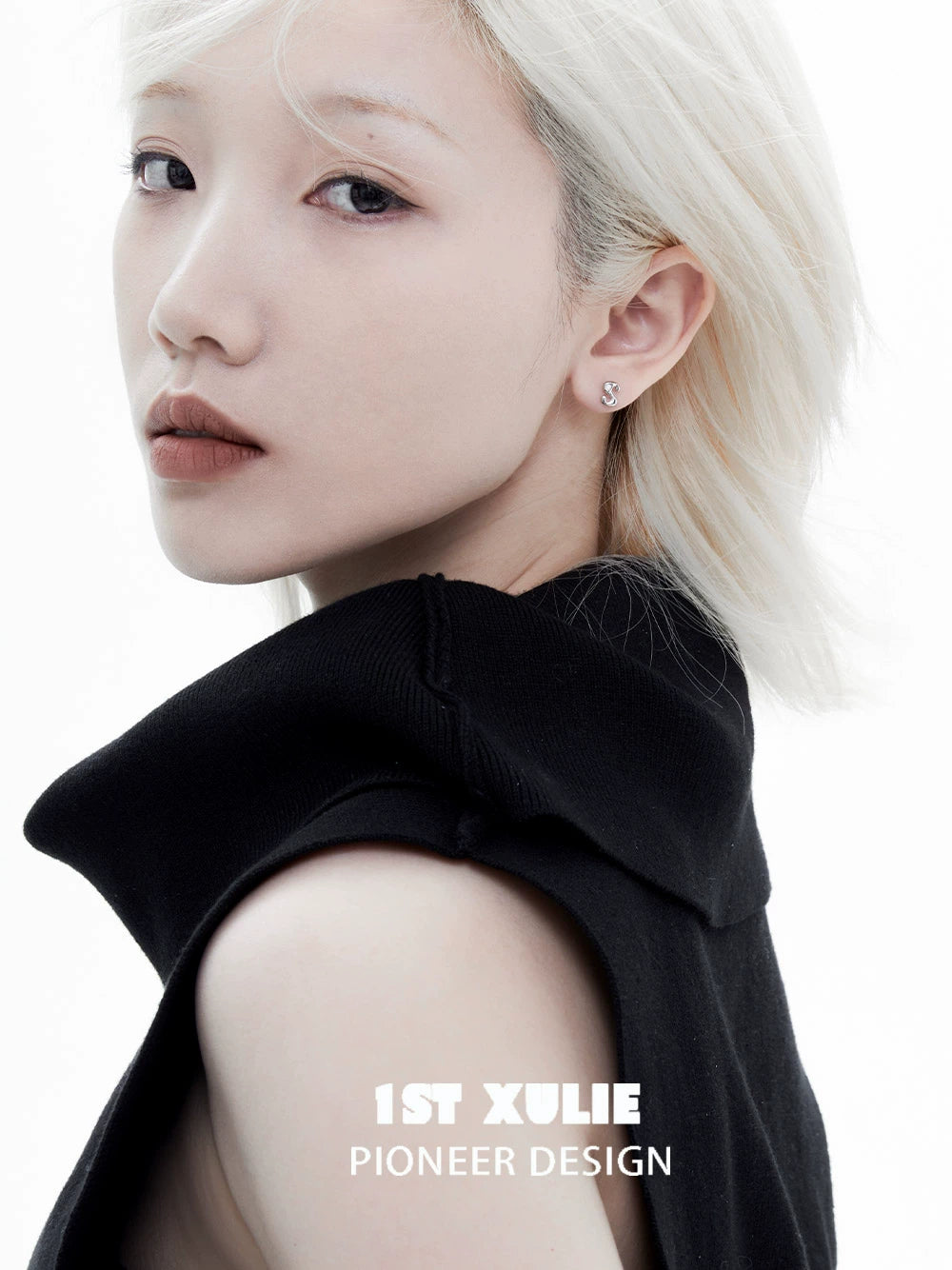 Model showcasing edgy letter silver stud earrings in a stylish black outfit
