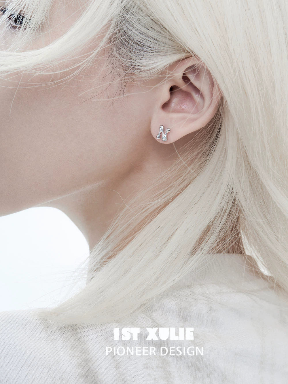 Edgy letter silver stud earrings worn on an ear, enhancing a stylish look