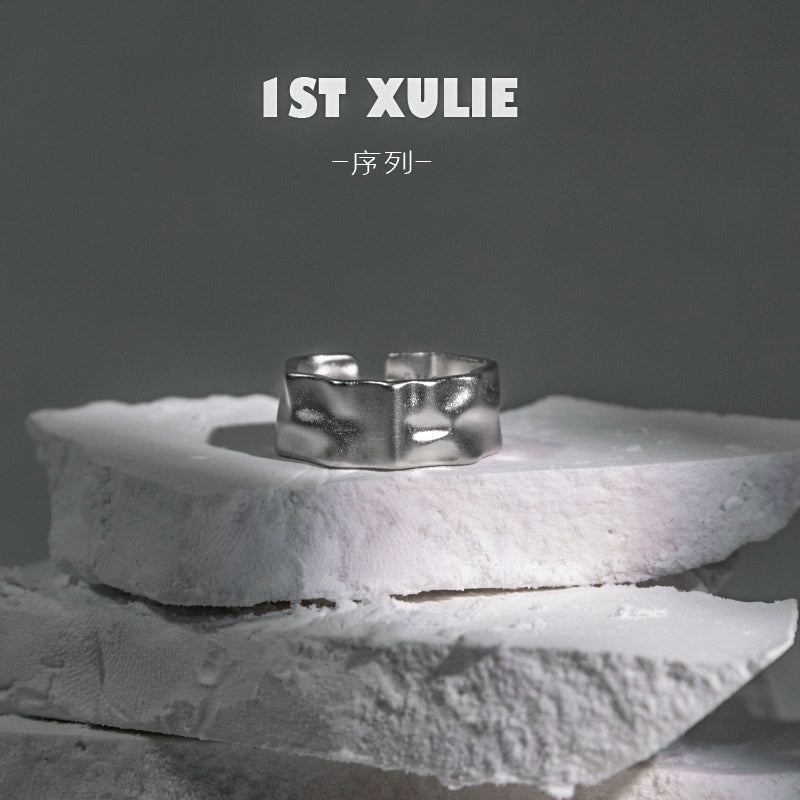 Futuristic silver ring displayed on textured white stone for contemporary fashion enthusiasts