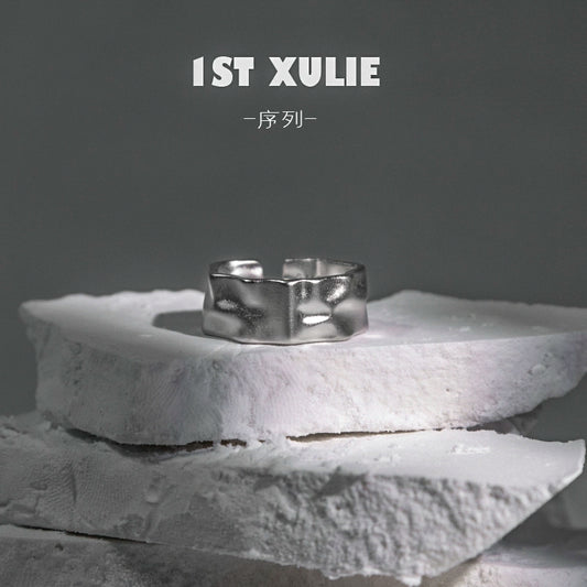Futuristic silver ring displayed on textured white stone for contemporary fashion enthusiasts