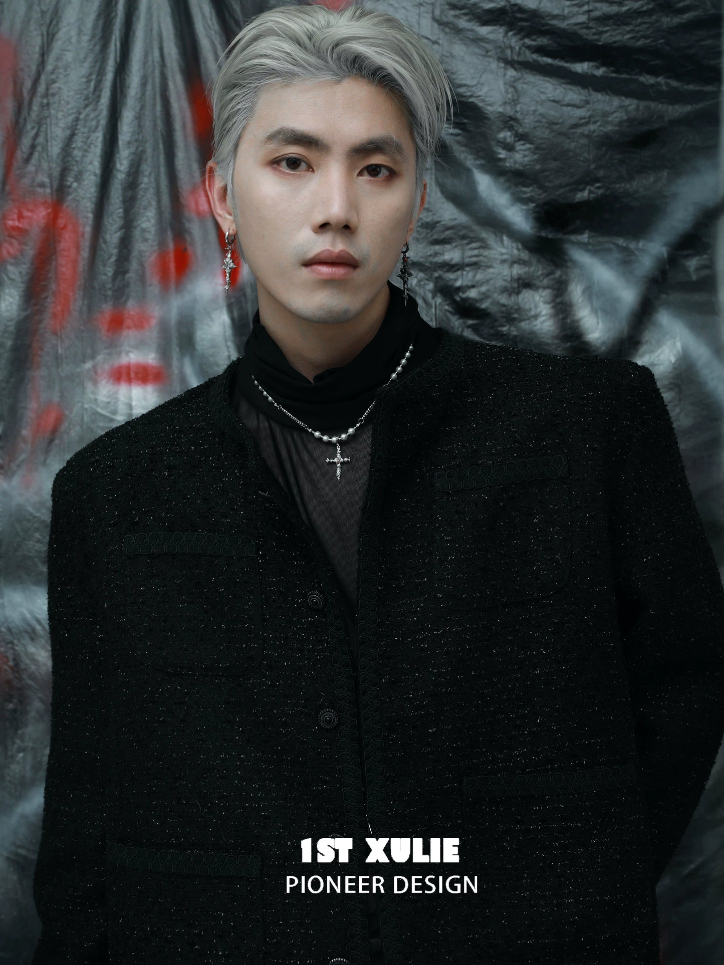 Gothic cross pearl necklace worn by model with gray hair and black attire against a textured backdrop