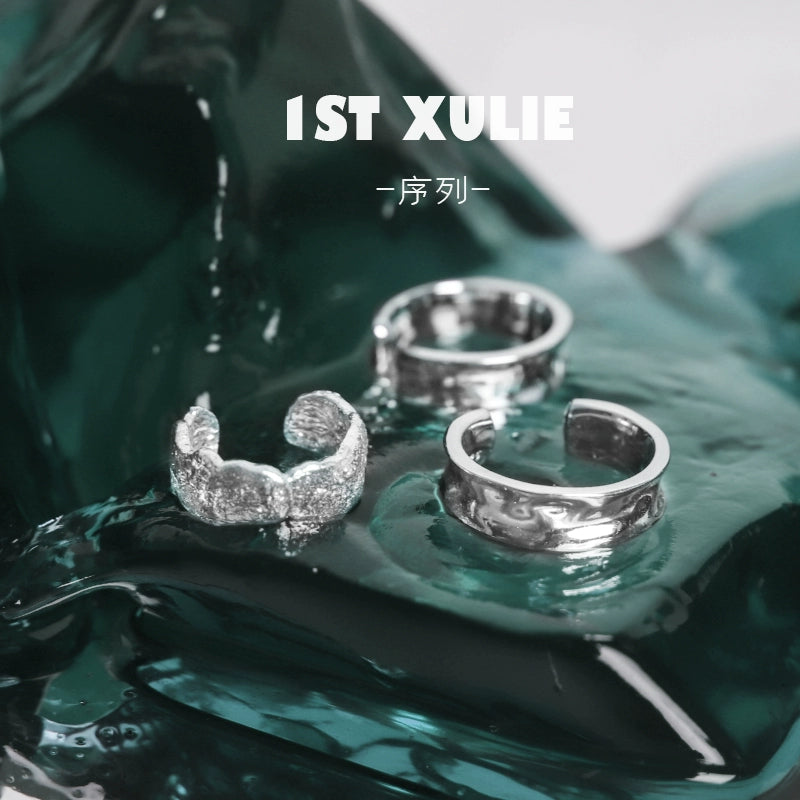 Three 1STXULIE minimalist frosted ear cuffs displayed elegantly on a shiny surface