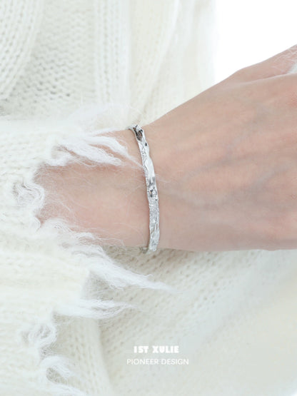Hand wearing a minimalist silver bracelet showcasing a sleek and elegant design