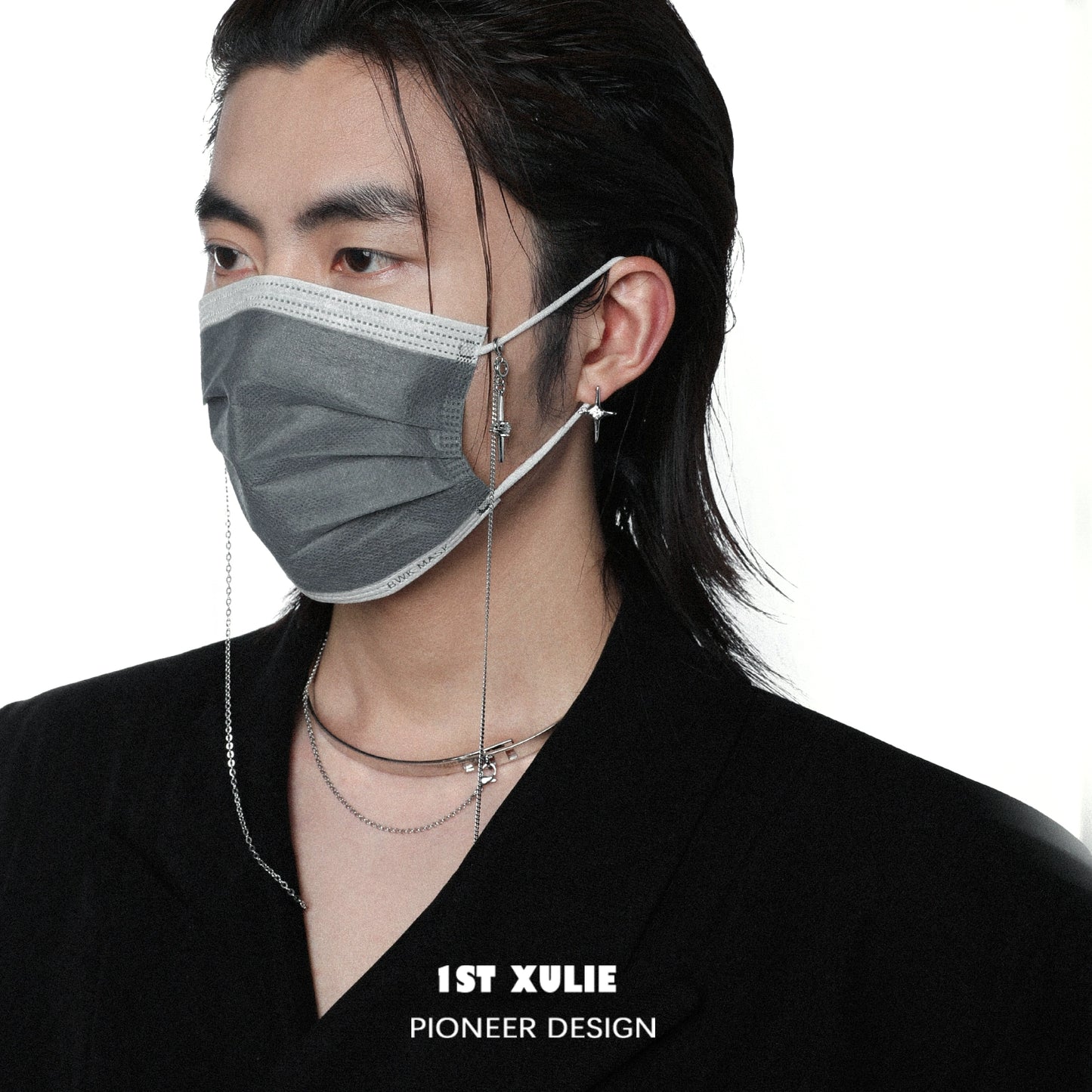 Model wearing a gray face mask and stylish mystic star necklace layered with silver chains
