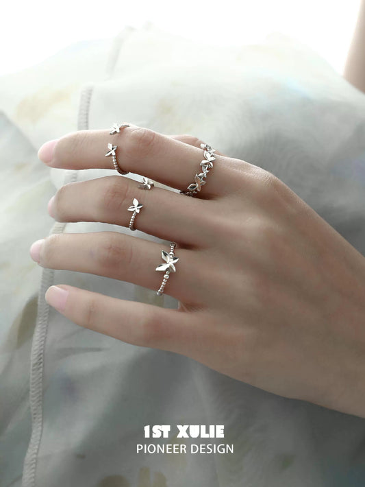 Elegant 1ST XULIE punk butterfly silver ring showcased among multiple rings on a hand