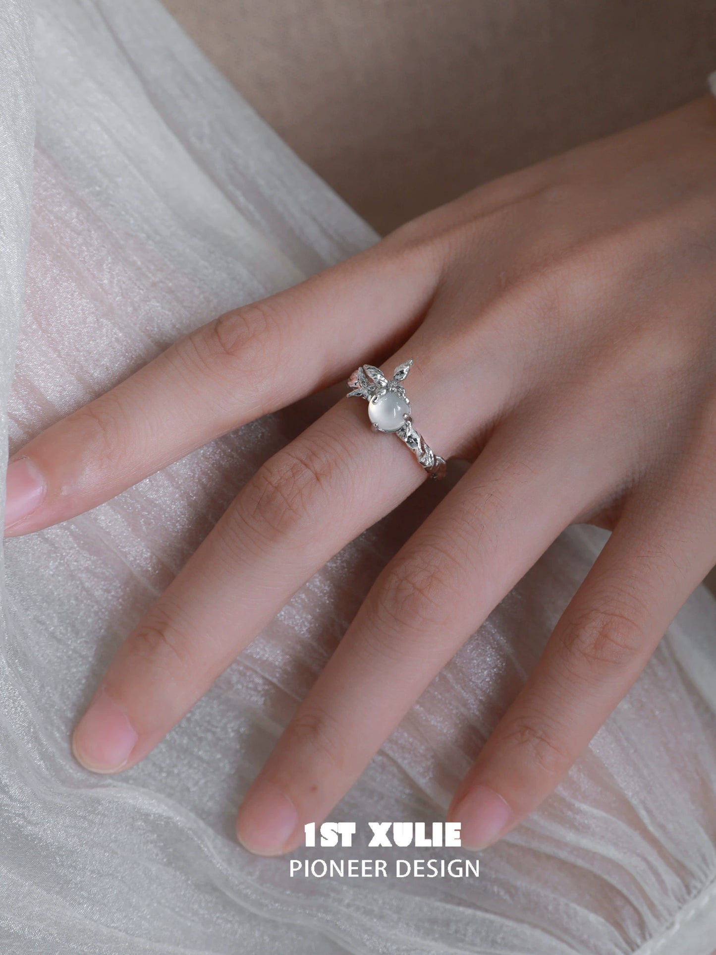 Elegant white agate butterfly silver ring showcased on a hand with a soft fabric background