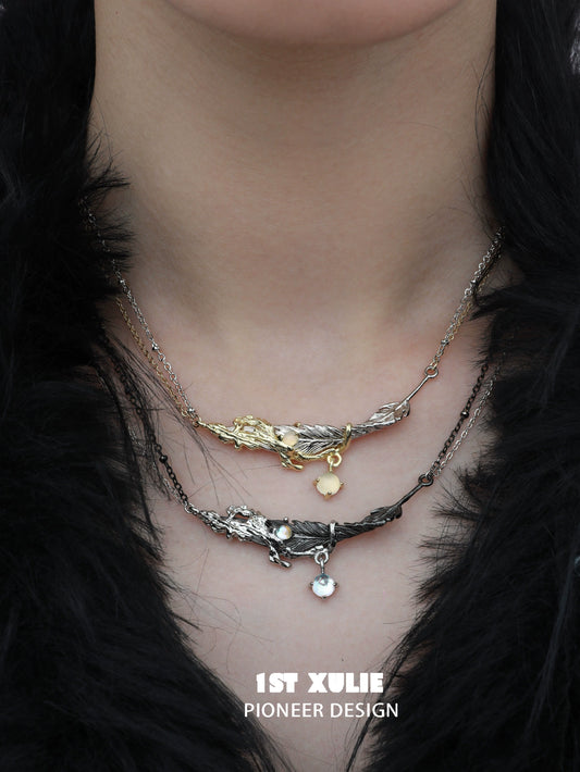Y2K feather necklace by 1ST XULIE featuring layered silver and gold designs with decorative charms