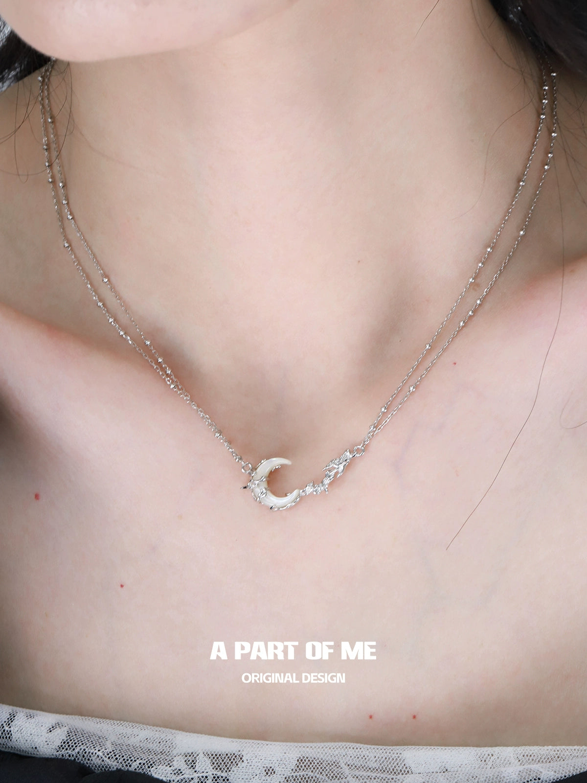 Elegant crescent moon necklace on a layered silver chain, perfect for stylish accessories.