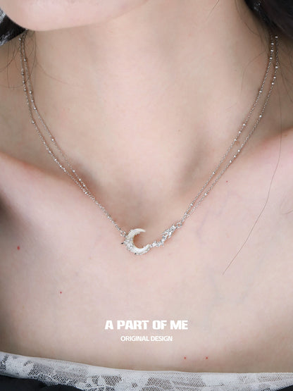 Elegant crescent moon necklace on a layered silver chain, perfect for stylish accessories.
