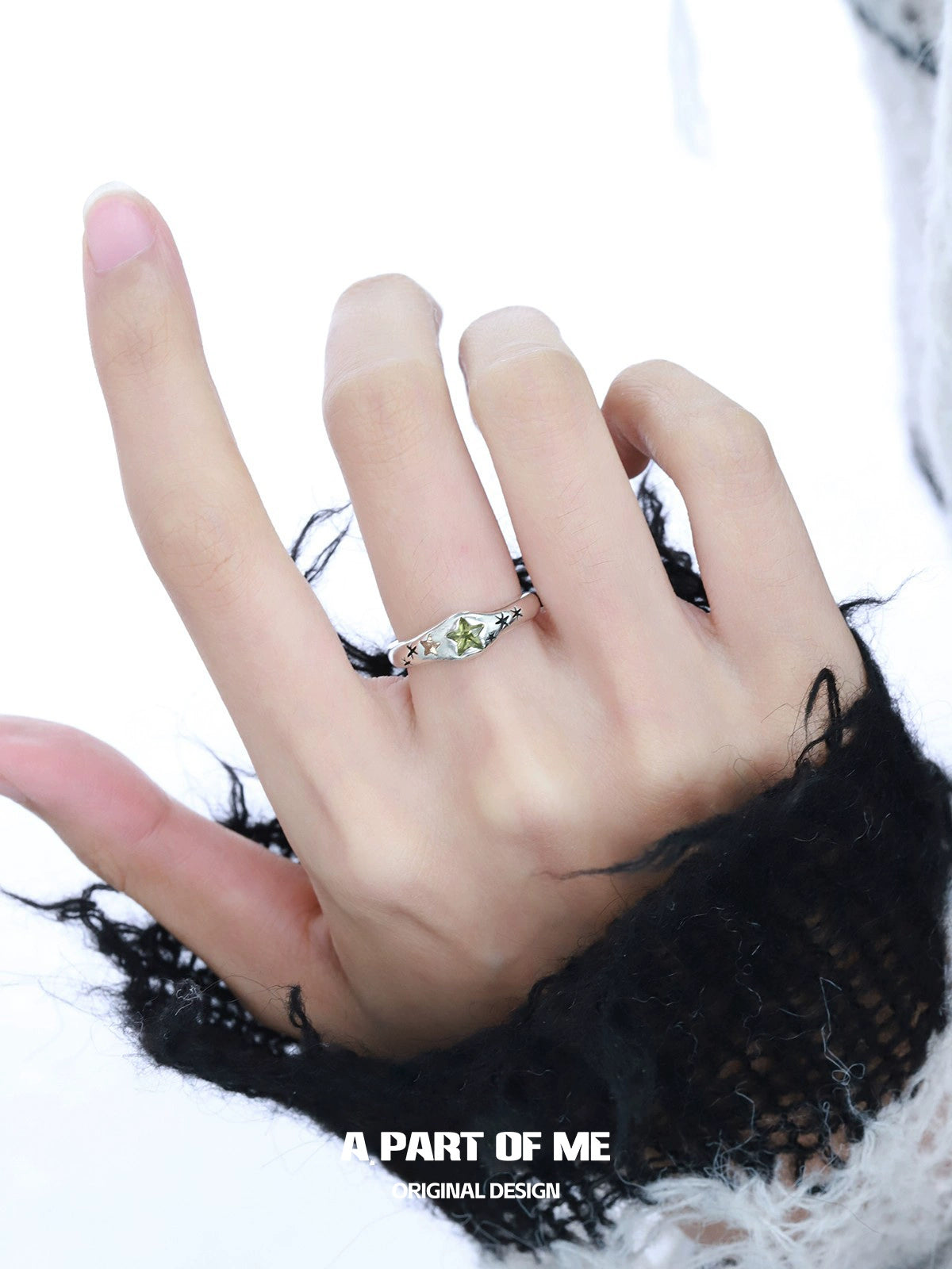 A hand wearing a delicate dreamy star ring with a silver setting and a unique gemstone design