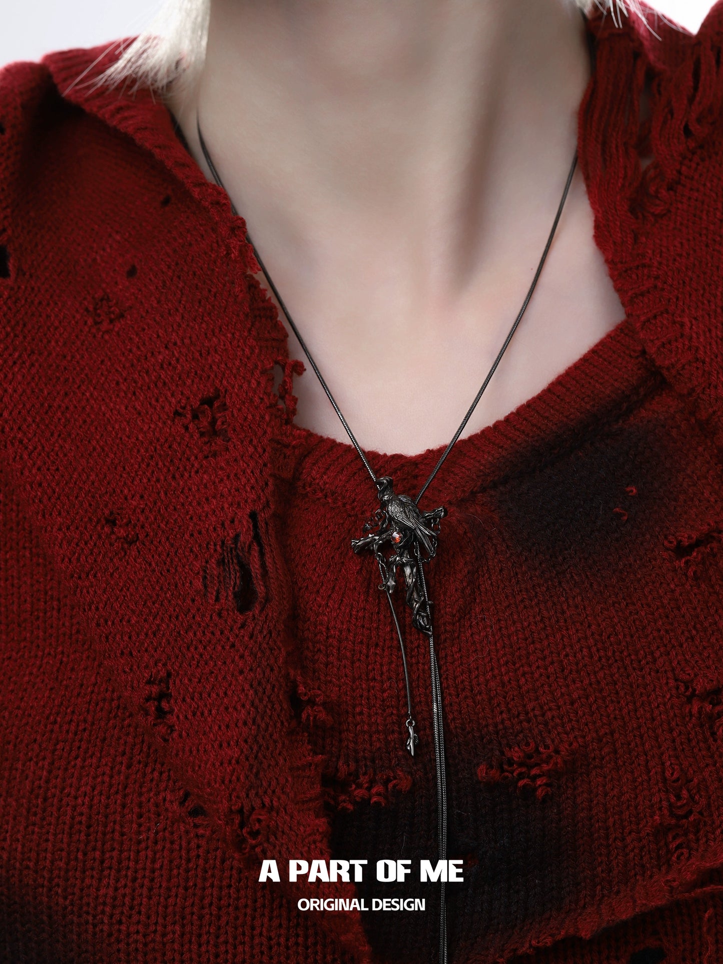 Gothic crow cross necklace displayed on a model wearing a distressed red sweater