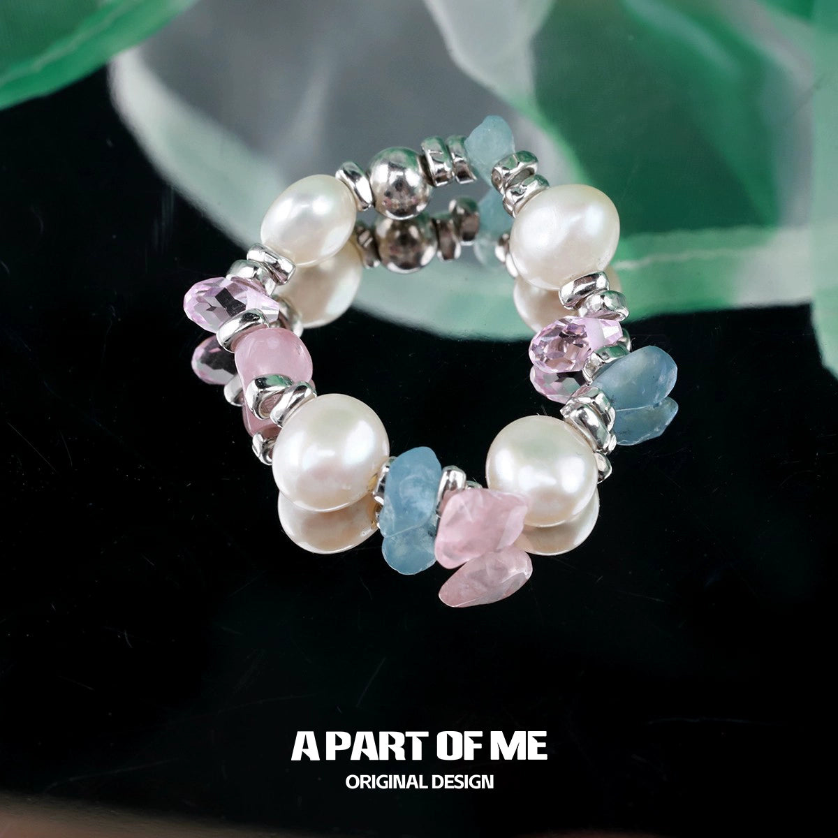 A colorful rainbow pearl ring featuring pink and blue gemstones and elegant pearl accents