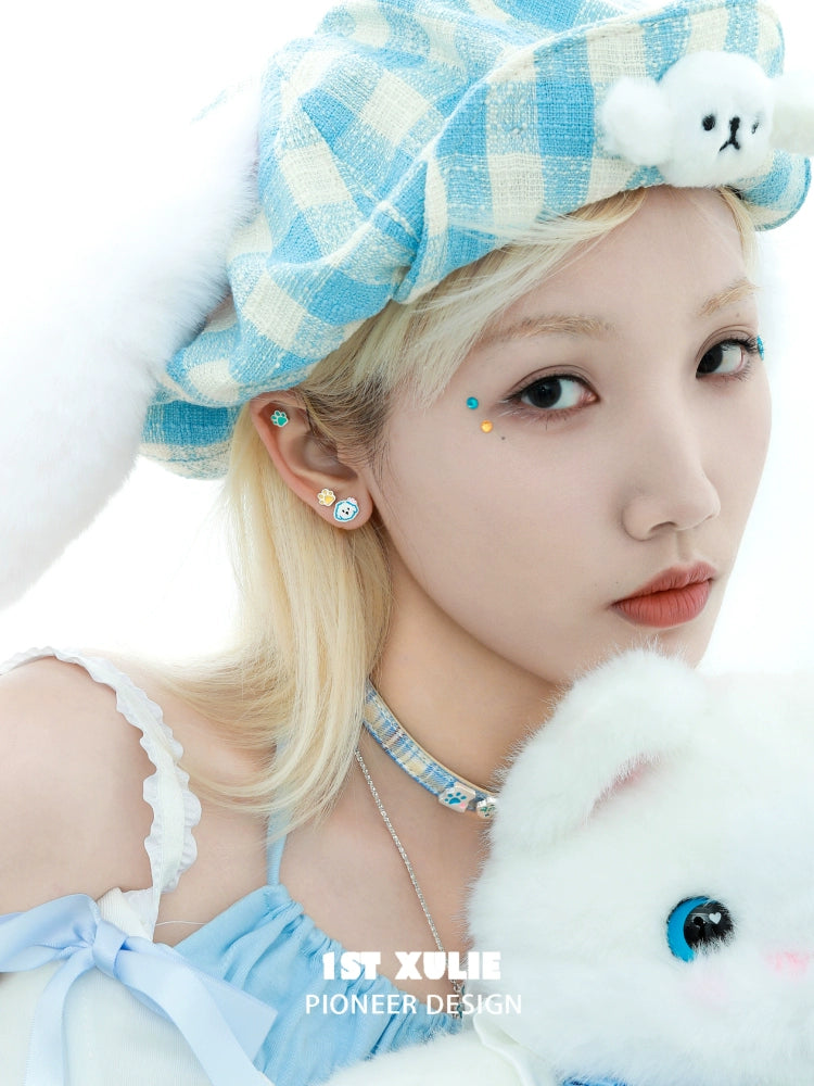 Angel cat and puppy earrings worn by a model with a blue hat and pastel outfit
