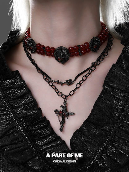 Gothic raven necklace layered with red beads and black chain for a dramatic style