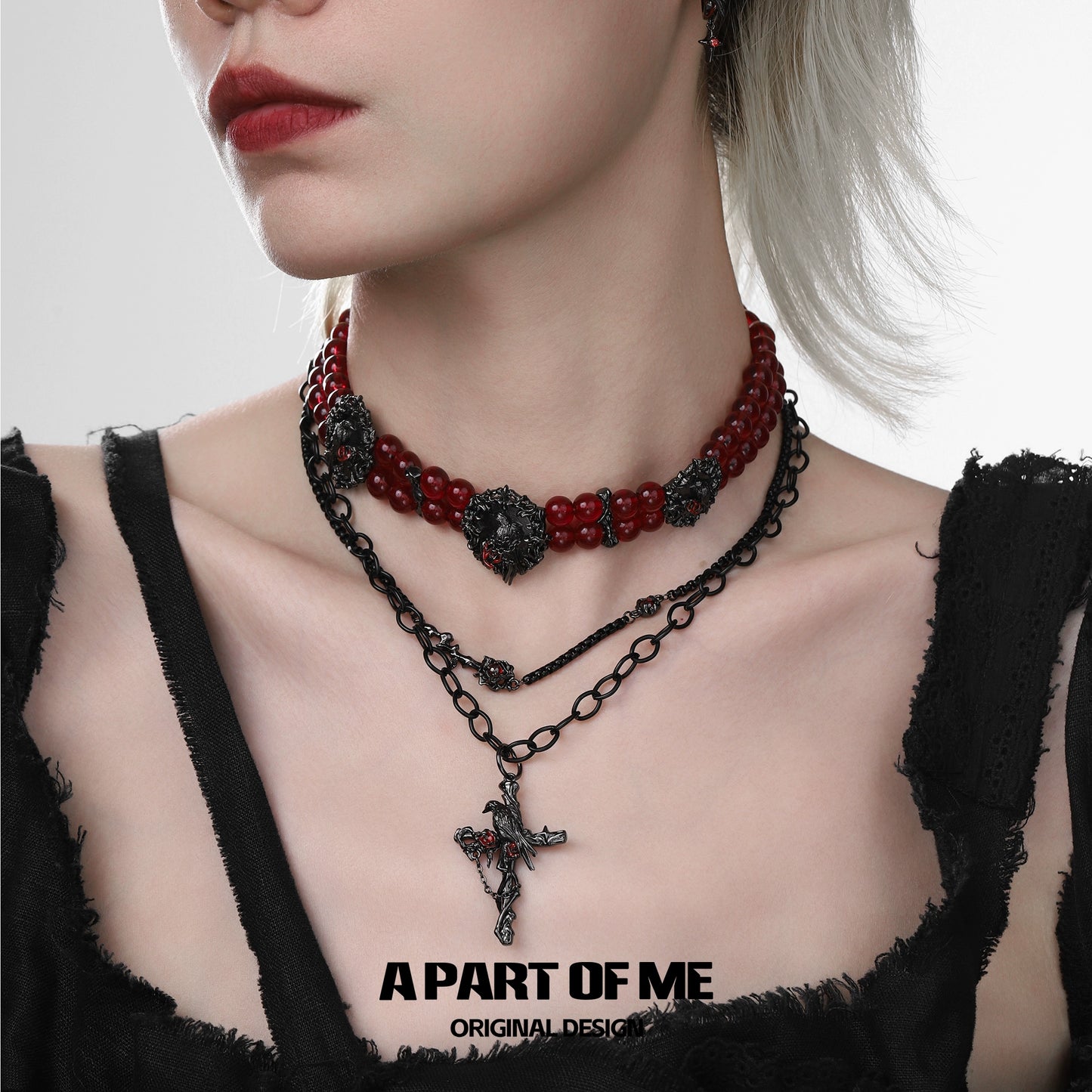 Gothic raven necklace layered with red beads and chain, perfect for a dark, edgy style