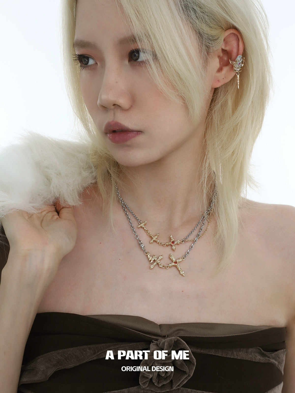 Stylish model wearing a liquid metal cross necklace layered with silver chains for a modern look