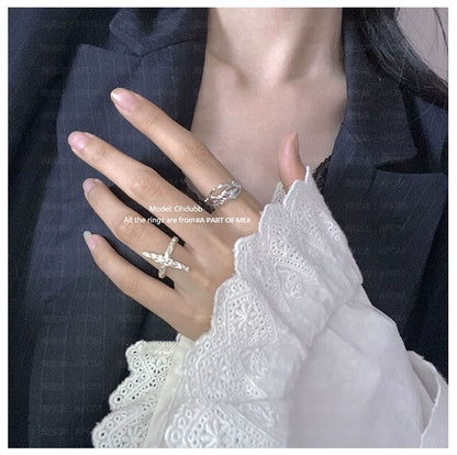 Model wearing a redemption cross silver ring paired with other delicate rings on a hand