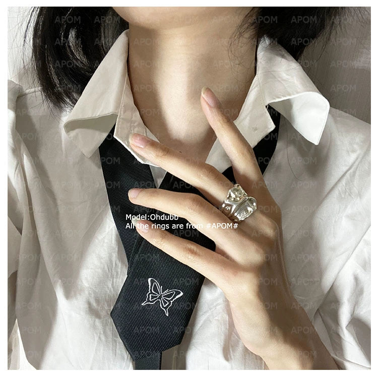 Model wearing a lace pleated silver ring on her finger, paired with a white shirt and black tie
