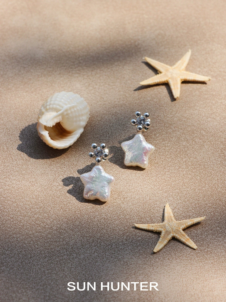 Elegant SUN HUNTER baroque pearl star earrings showcased with seashells and starfish