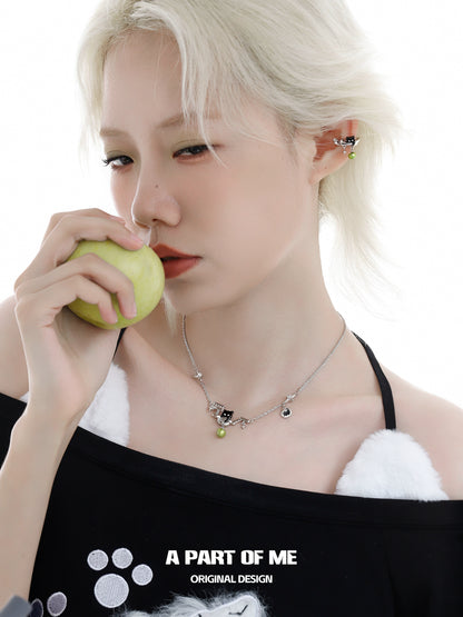 Model wearing a stylish black cat necklace from A PART OF ME while holding a green apple