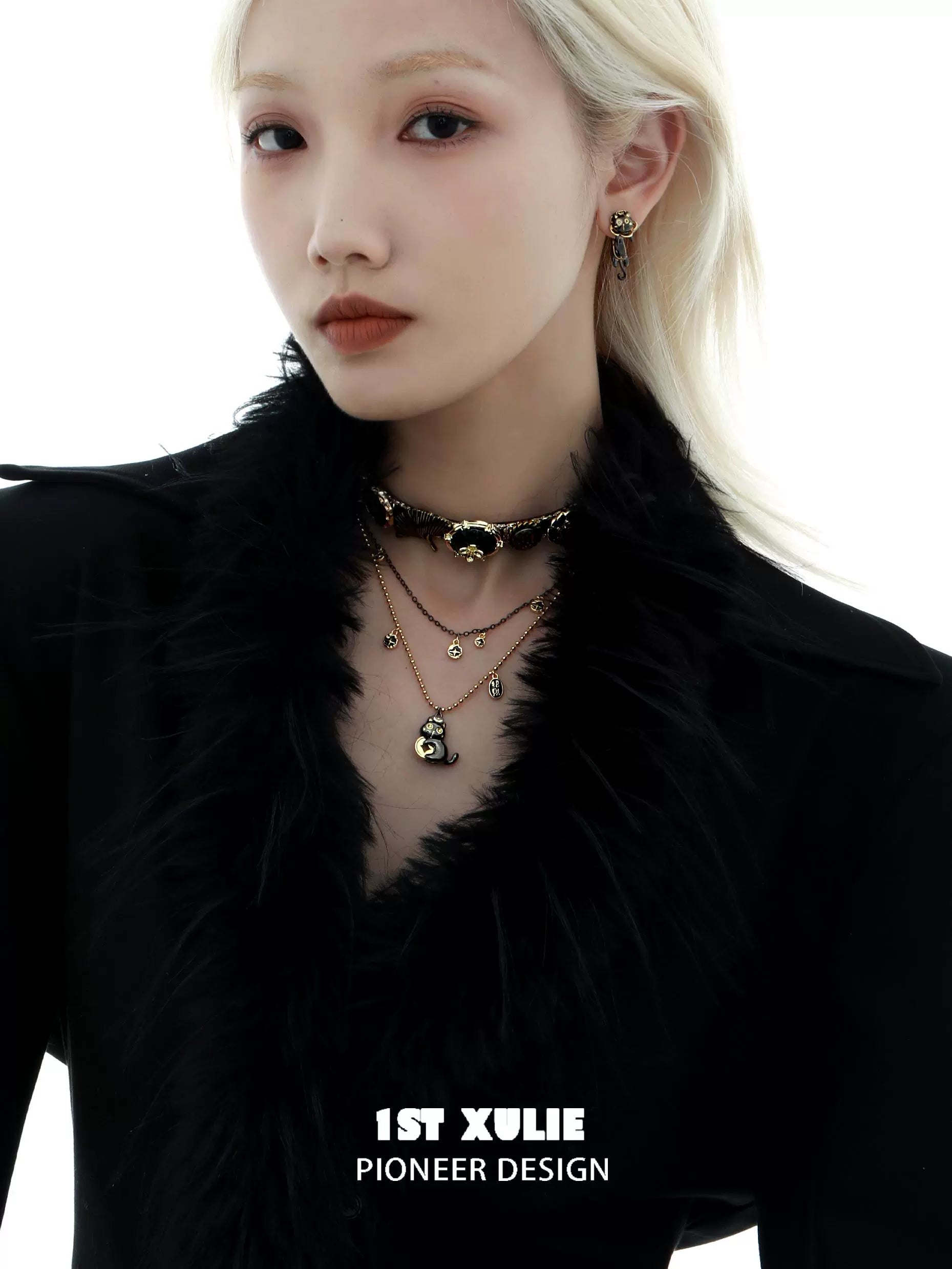 Stylish black gold cat necklace layered with matching earrings and a chic outfit