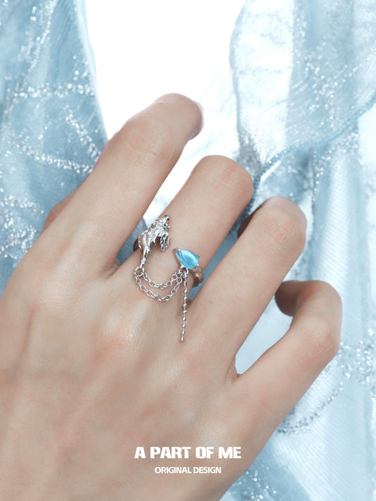 Silver A PART OF ME blue conch chain ring on a hand with soft blue fabric background