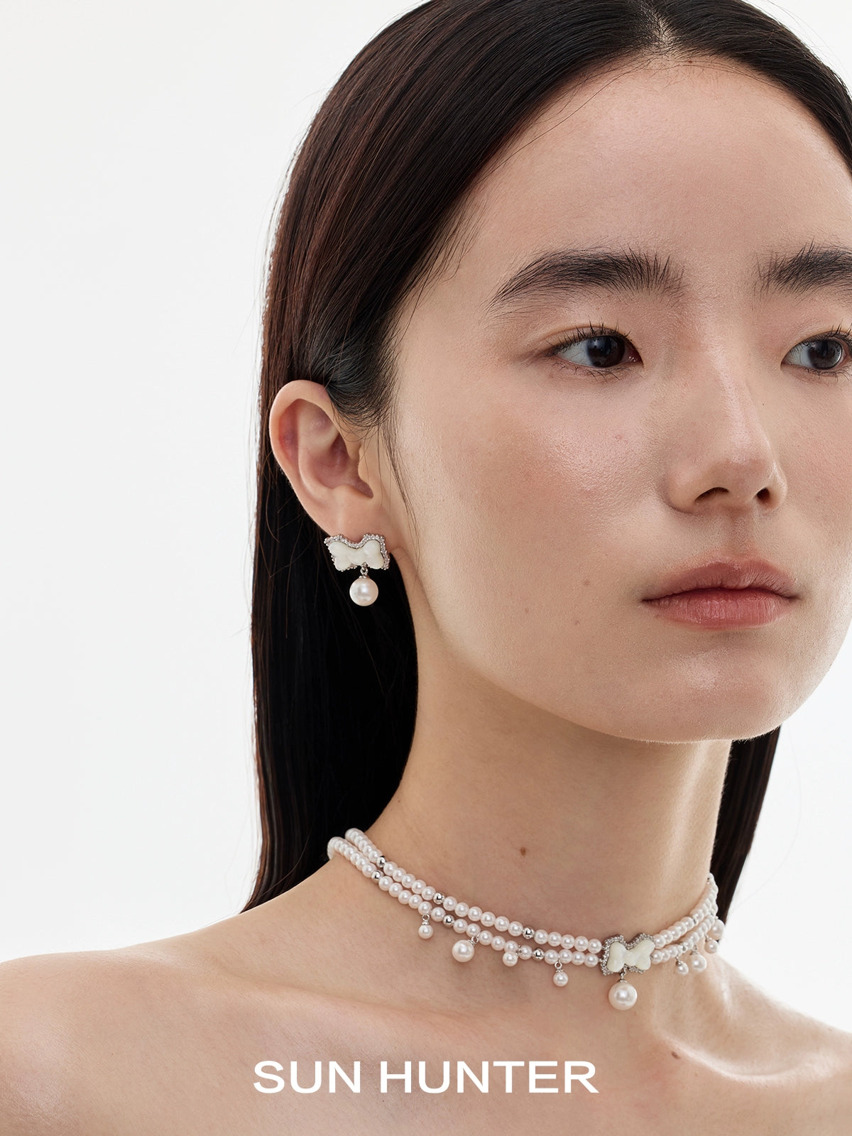 Elegant SUN HUNTER bow pearl earrings paired with a matching pearl necklace