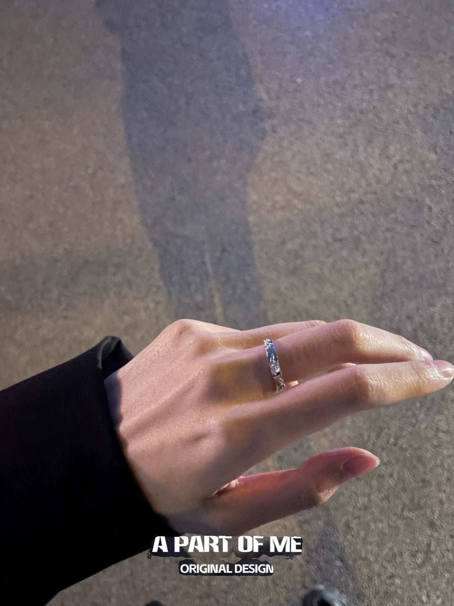 Elegant broken silver ring displayed on a hand against a soft-textured background