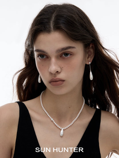 Elegant SUN HUNTER brushed teardrop earrings paired with a matching pearl necklace on a model