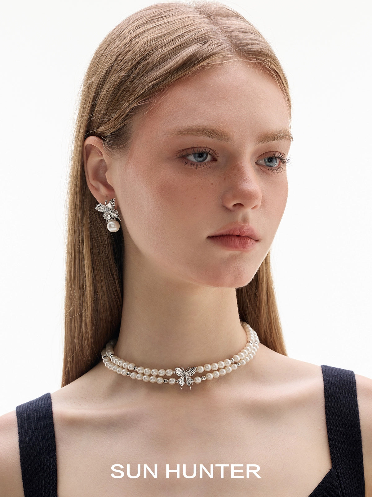 Elegant SUN HUNTER butterfly pearl earrings paired with a matching pearl necklace worn by a model