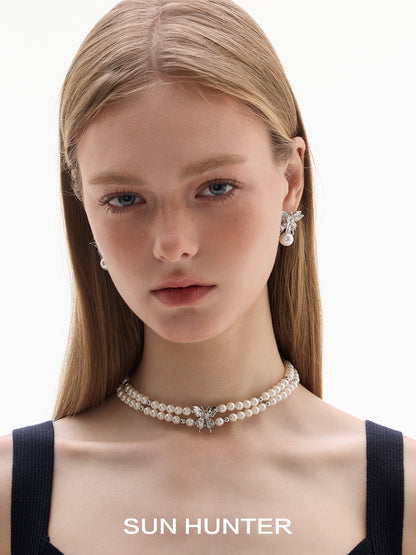 Elegant butterfly pearl earrings elegantly displayed on a model with a pearl choker necklace