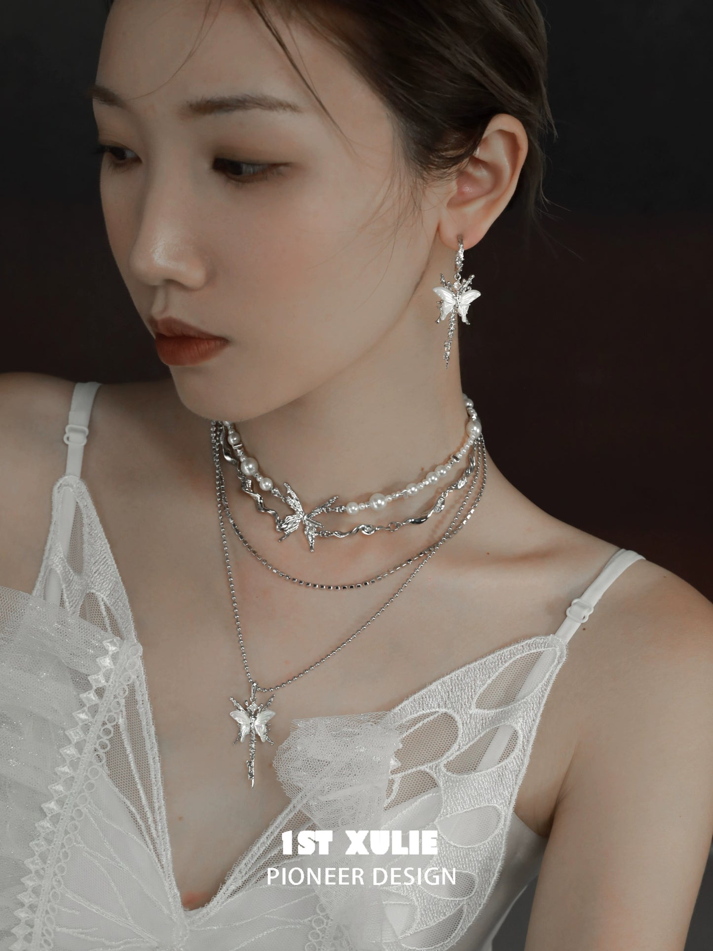 Model wearing butterfly tassel shell earrings with layered silver necklaces and a stylish outfit