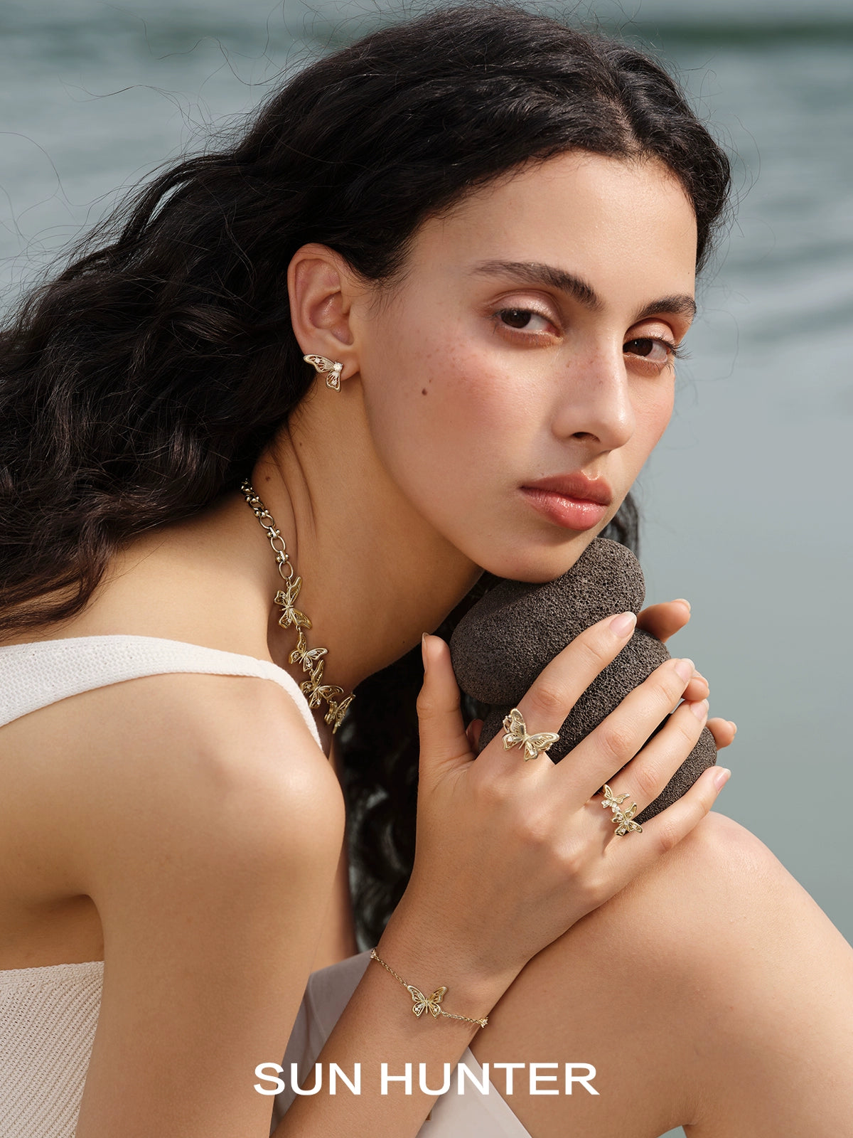 Stylish butterfly wing earrings by SUN HUNTER showcased on a model by the water