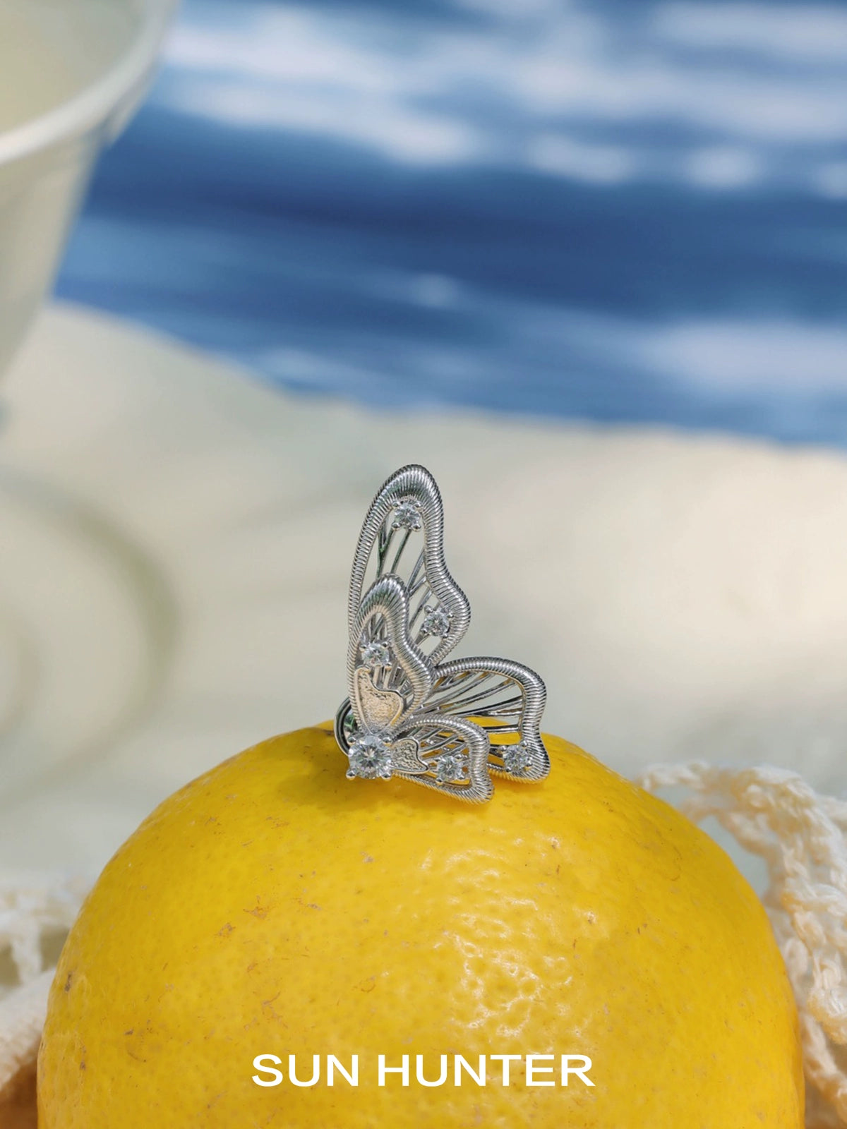 Elegant SUN HUNTER butterfly wing earrings showcased on a lemon for vibrant contrast