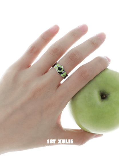 Cat and dog silver ring designed with colorful accents, worn on a hand holding a green apple