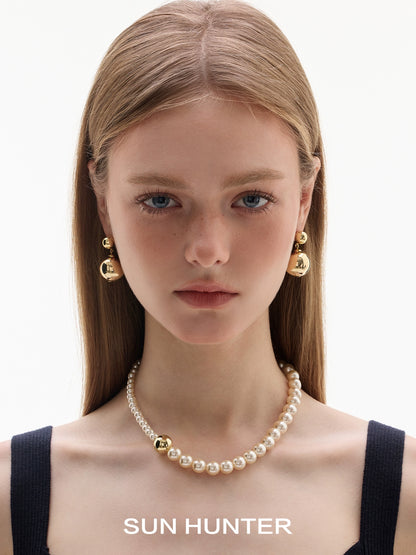 Stylish celestial planet gravity earrings by SUN HUNTER showcased on a model with a pearl necklace