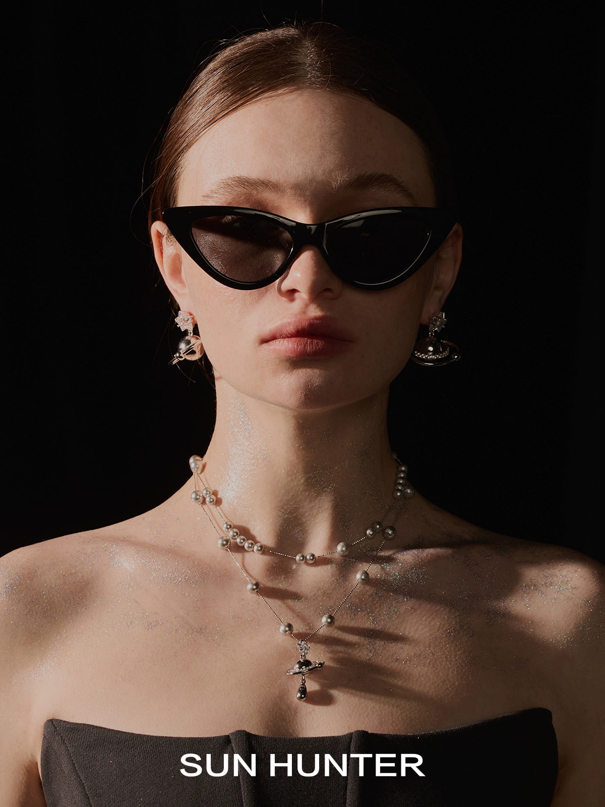 Model wearing SUN HUNTER cosmic planet star earrings with stylish black sunglasses