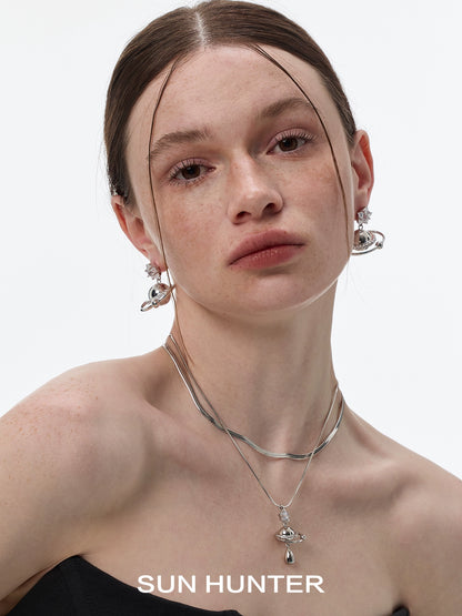 Model wearing SUN HUNTER cosmic planet star earrings with a stylish silver necklace
