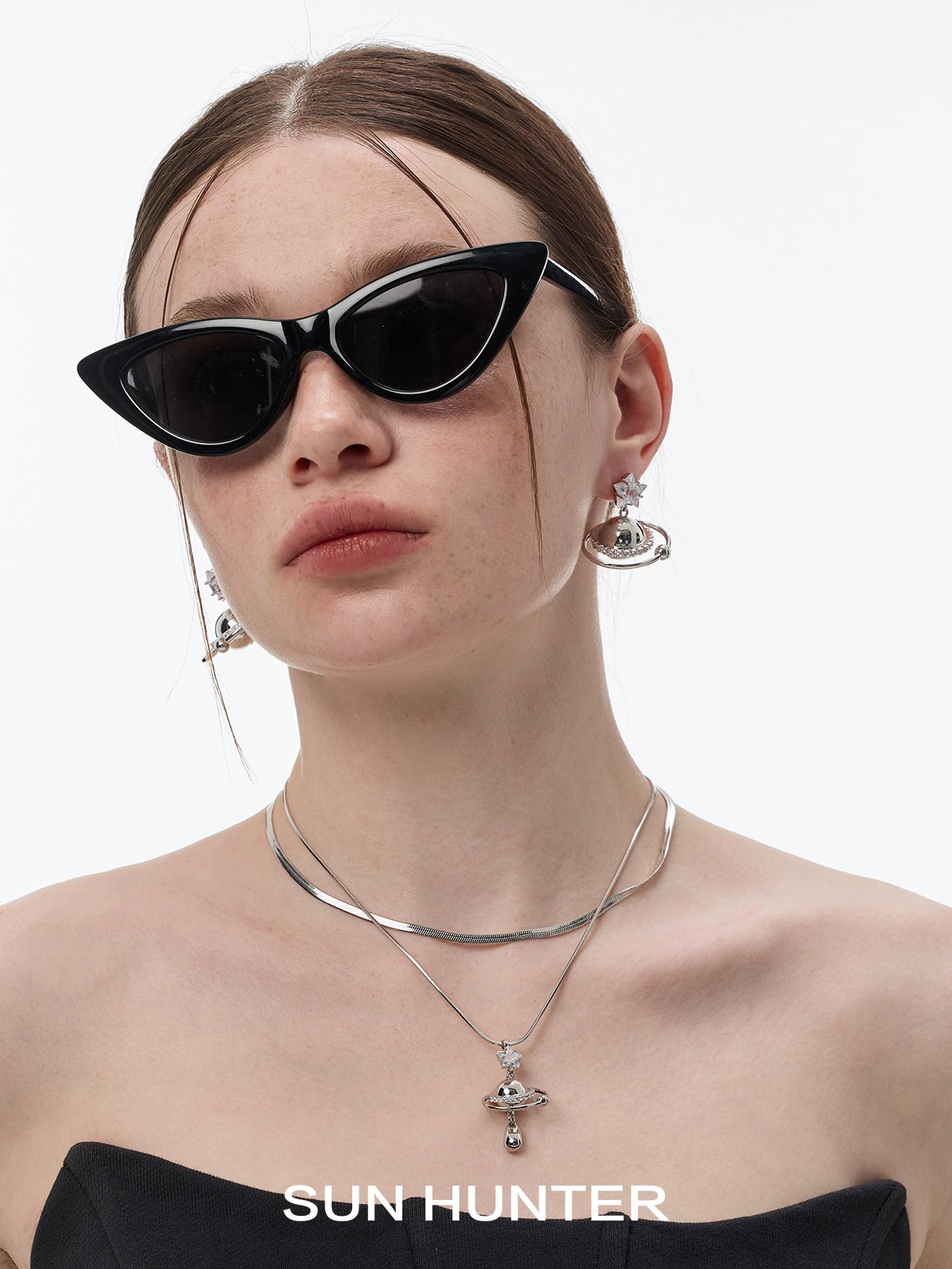 Trendy model wearing SUN HUNTER cosmic planet star earrings with stylish cat-eye sunglasses