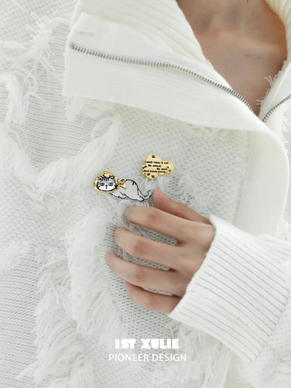 Cute cat silver brooch featuring playful design attached to a white fringed sweater