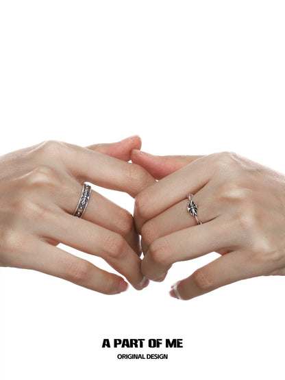 Two hands wearing a dark iris vintage ring alongside a delicate band, showcasing unique design details
